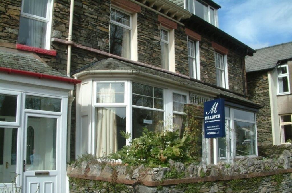 Millbeck Guest House, a traditional Lakeland stone cottage in Windermere with its blue Millbeck sign