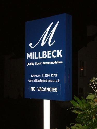The blue Millbeck sign at night: Millbeck Quality Guest Accommodation